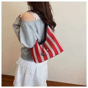 Detail of red and white striped knit shoulder bag with black leather strap and metal ring