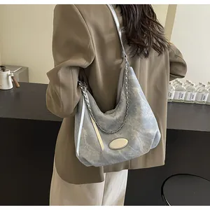 Detail shot of light blue denim hobo bag with silver metal chain and thin shoulder strap