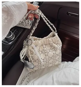 Detalle del bolso bombonera crema con pedrería, colgantes de perlas y dijes de corazón