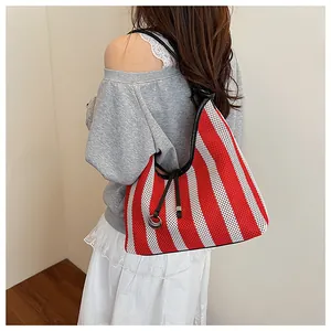 Detailed close-up of a red and white striped mesh tote bag with black shoulder straps