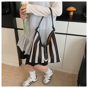 Detail of black and white striped woven tote bag with leather strap and knot accent