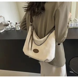 Detail of a large cream hobo bag with woven chain and brown leather zipper pull