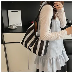 Detail of black and white woven mesh tote bag featuring leather straps and metal rings