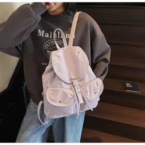 Détail du sac à dos en nylon lilas avec deux poches avant porté par un mannequin