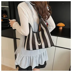 Detail of black and white striped knit shoulder bag with thin leather strap closure