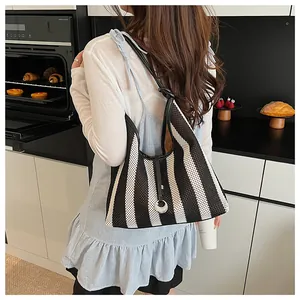 Detailed view of black and white striped woven shoulder bag with leather handle and ring pendant
