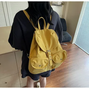 Détail d'un sac à dos en toile jaune avec fermeture à boucle et doubles poches avant