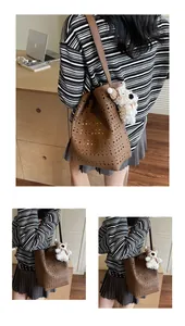 Close-up of brown hollow-out bucket bag with a cute white plush puppy charm