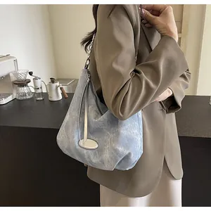 Detail of light blue distressed canvas tote with silver chain strap and metal plaque