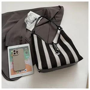 Detailed top view of black and white striped woven tote bag with leather straps and metal hardware