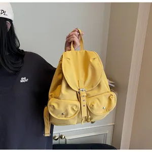 Détail du sac à dos jaune vif avec deux poches frontales et fermeture à boucle argentée