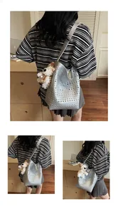 Detail showing silver hollow-out shoulder bag with large circular perforations and puppy charm