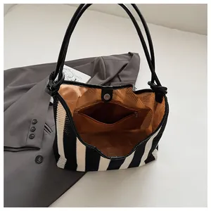 Detail view of woven striped tote bag showing magnetic clasp and brown inner lining
