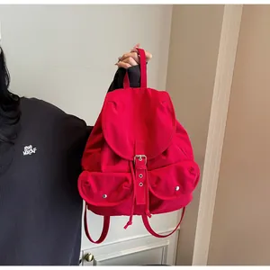 Détail d'un sac à dos vintage rouge avec doubles poches frontales et boucles argentées