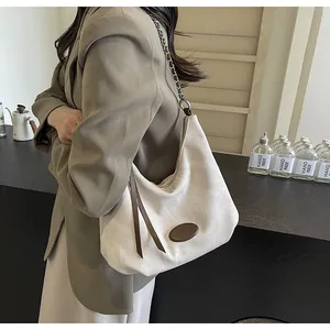Detail of off-white canvas hobo bag with brown leather accents and silver chain strap
