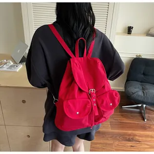Détail d'un sac à dos en toile rouge avec deux poches avant et boucles métalliques