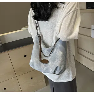 Detail of blue canvas hobo bag with vintage leather strap and bronze metal chain
