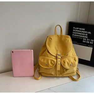 Détail d'un sac à dos jaune avec fermeture à cordon et deux poches avant pratiques