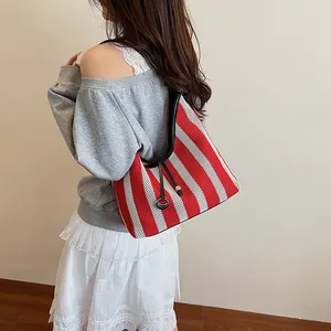 Fashionable woven shoulder bag with red and white stripes and black strap on model
