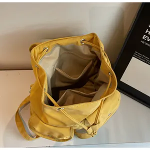 Vue de dessus du sac à dos jaune à cordon montrant la doublure beige et la poche zippée
