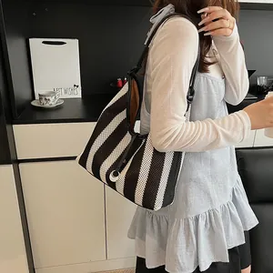 Fashionable woven tote bag with black and white stripes and silver round buckle closure