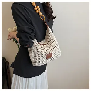 Detail of crochet weave texture and large wooden bead shoulder strap on a beige beach bag