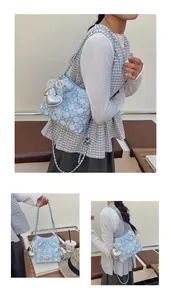 Detalle de bolso acolchado azul claro con asa de perlas y un colgante de corazón