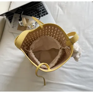 Detail view of yellow laser-cut bucket bag with drawstring liner and plush charm