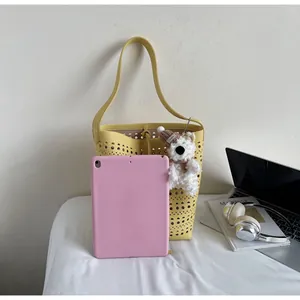 Detail of yellow hollow-out tote bag showing interior space and pink tablet for size reference