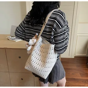 Detailed laser-cut hollow pattern on white faux leather tote with plush dog charm