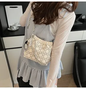 Detalle del bolso de hombro beige con pedrería, acolchado geométrico y colgante perla