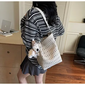 Detail of hollow-out bucket bag with a cute plush puppy charm and floral laser-cut pattern
