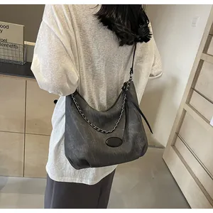 Close-up of washed gray crescent tote bag with metallic chain and long zipper detail