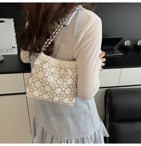 Detalle de bolso tipo cubo con malla de diamantes y correa de cadena plateada