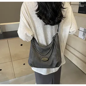 Detail view of charcoal grey hobo bag with silver chain and matte texture on a shoulder