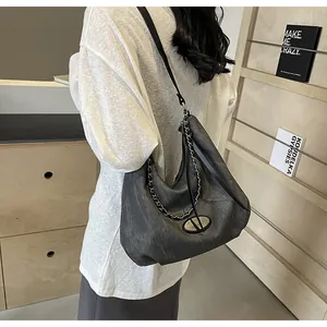 Detail of grey hobo bag with black leather strap and silver metal chain accessory