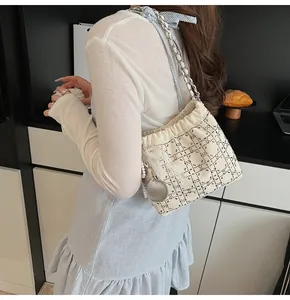 Vista de hombro de bolso saco blanco roto con patrón de rombos de cuentas y colgantes