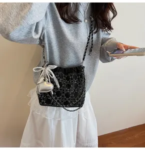 Detalle de bolso tipo cubo en terciopelo negro con pedrería y colgante de corazón