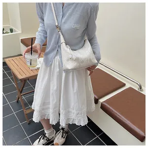 Detail of hobo handbag in off-white stone texture with elegant bead pendant and strap