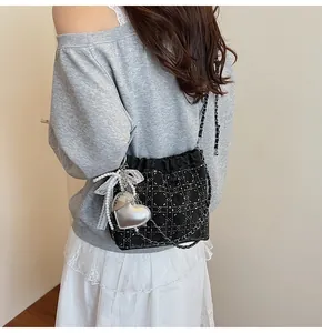 Detalle de bolso cubo acolchado negro con tachuelas plateadas y colgante de corazón
