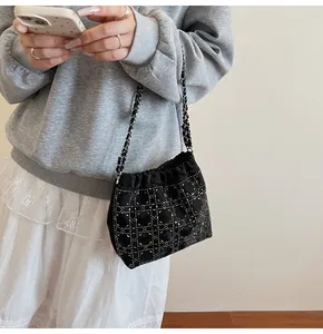 Detalle de bolso saco negro con cordón, tachuelas plateadas y correa de cadena metal