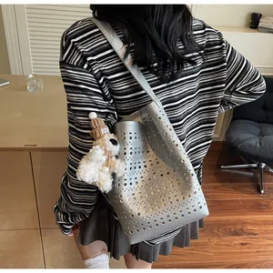 Detail of silver hollow-out bucket bag featuring a cute plush dog charm with Lovely tag
