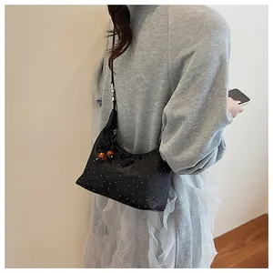 Detail of black polka dot shoulder bag with wooden bead charm on light grey knit outfit