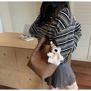 Detail of hollow-out brown bucket bag with a cute plush bear charm in a cozy room