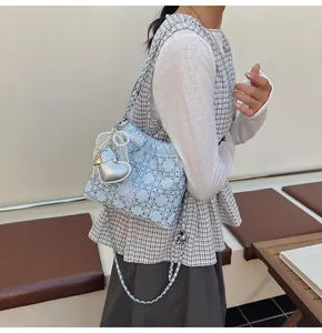 Detalle del bolso tipo cubo de satén acolchado azul claro con pedrería y cadena