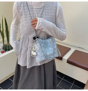 Detalle del bolso vaquero azul claro con celosía de diamantes, perlas y dijes corazón