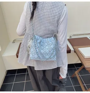 Detalle del bolso tipo cubo azul claro con pedrería, tachuelas y colgante de corazón