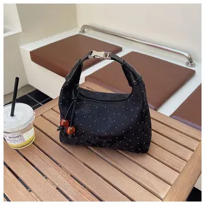 Close-up of black polka dot handbag with amber bead charms on a wooden cafe table
