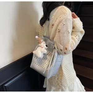 Detail of silver hollowed bucket bag with cute plush puppy charm worn by a model