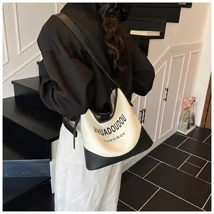 Détail du sac seau minimaliste en toile crème avec base en cuir noir et bandoulière